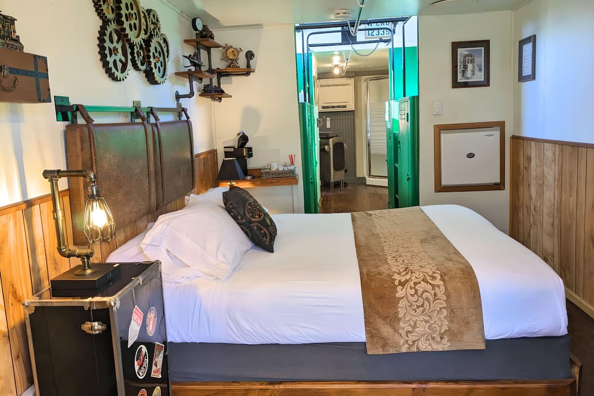 A room with a bed, a desk, and a wall-mounted clock.