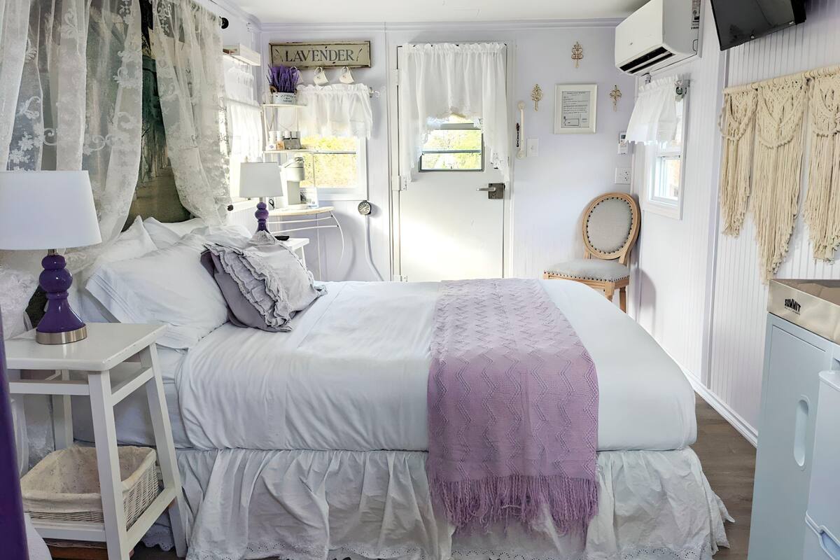 A bedroom with a bed, bedside table, lamp, and a dresser.