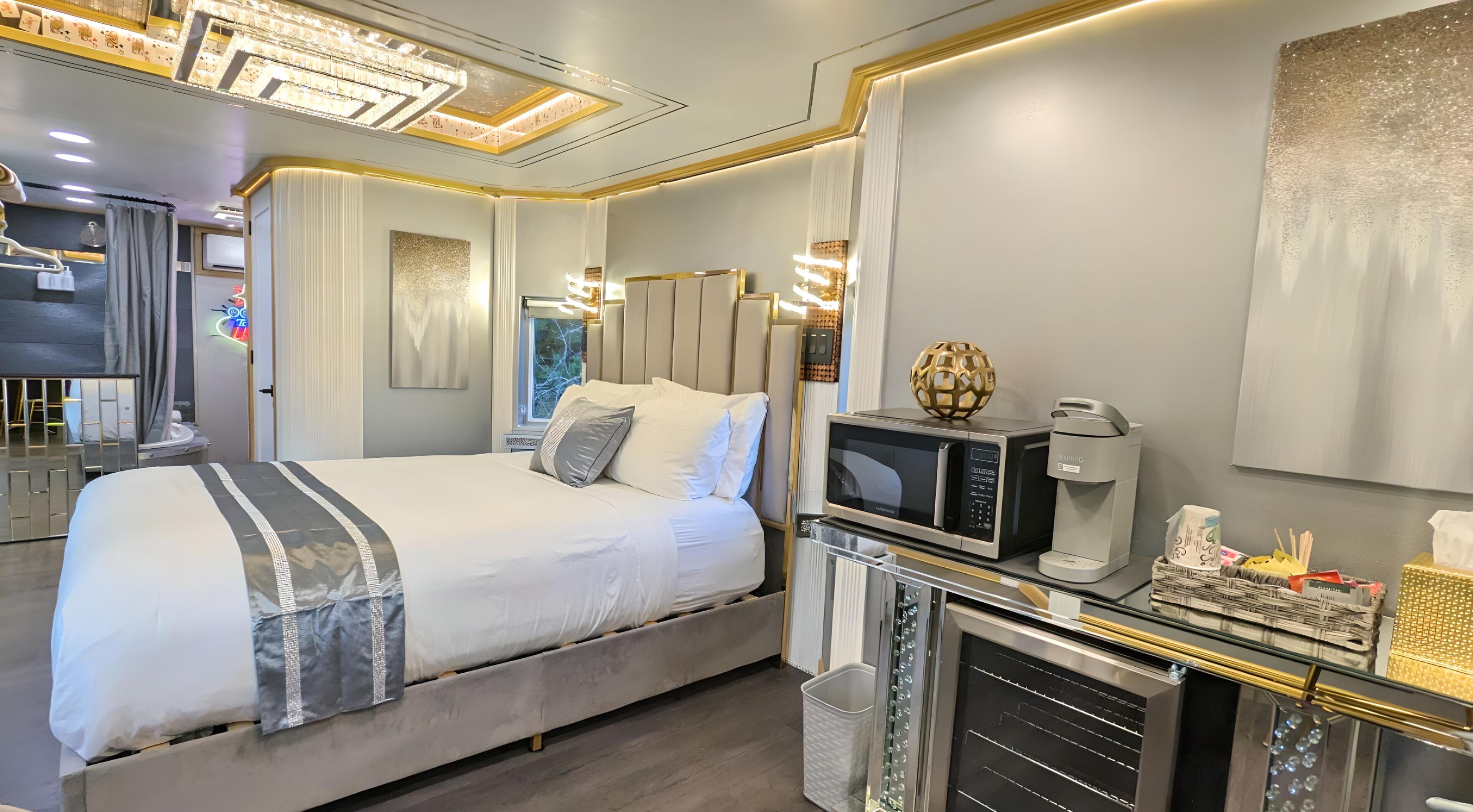 A modern hotel room with a large bed, a minibar, a coffee machine, and a television.