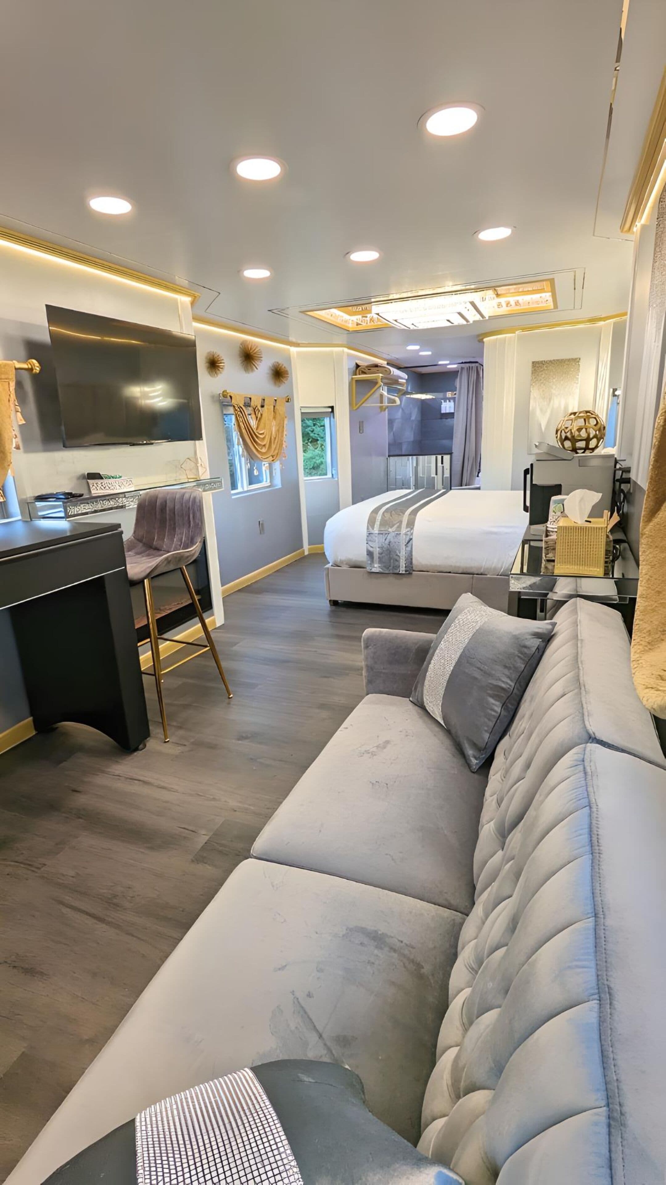 A modern living room with a sofa, a desk, and a TV.