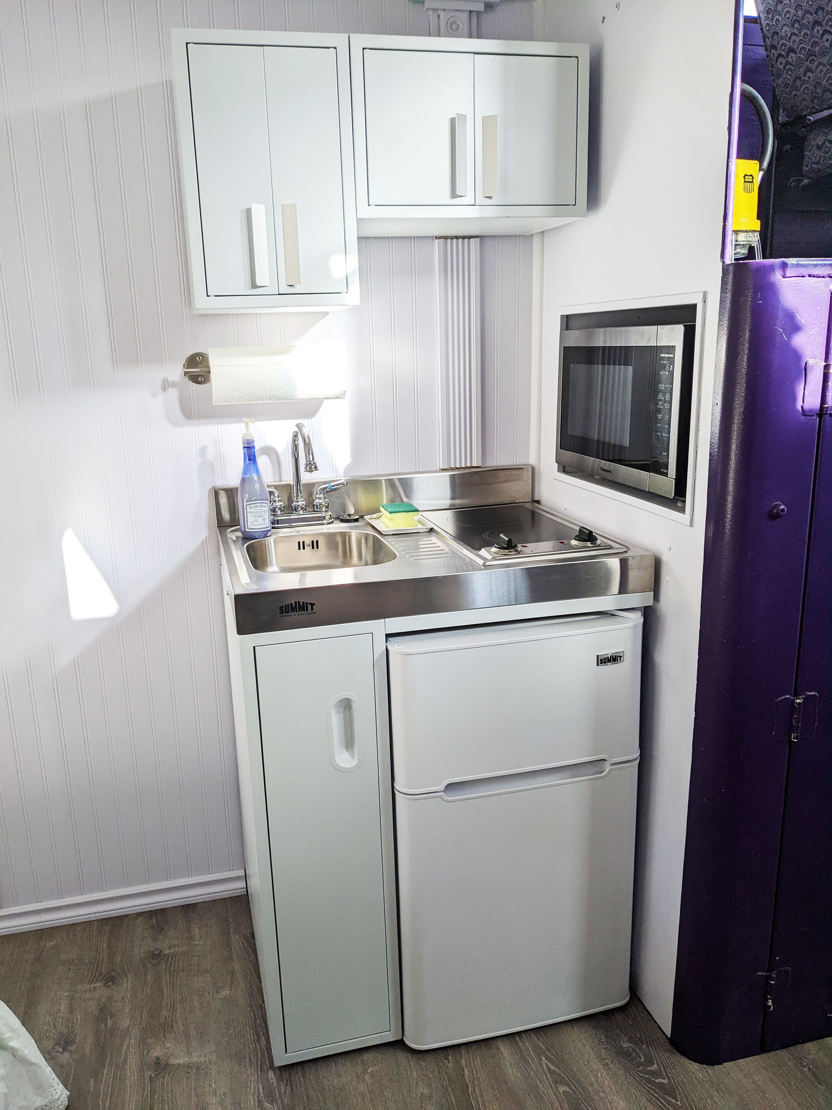 A compact kitchenette with a sink, a microwave, and a refrigerator.