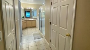 A hallway with white doors, a tiled floor, and a ceiling light. - Cozy 3Be/2Ba Home, Heated Pool/Spa, near Orlando-Disney, Universal, Golf Course. (Davenport)