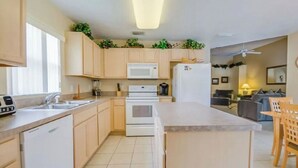 A modern kitchen with light wood cabinets, a central island, a microwave, a stove, and a dishwasher. - Cozy 3Be/2Ba Home, Heated Pool/Spa, near Orlando-Disney, Universal, Golf Course. (Davenport)