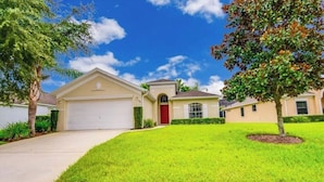 A residential house with a garage, a red door, and a well-maintained lawn. - Cozy 3Be/2Ba Home, Heated Pool/Spa, near Orlando-Disney, Universal, Golf Course. (Davenport)