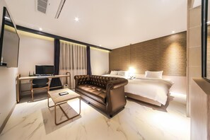 A modern hotel room with a leather sofa, a bed with white linens, a desk with a computer, and a large window with curtains. - Hound Hotel Seomyeon-bumcheon (Busan)