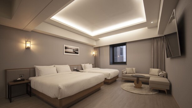 A modern hotel room with two beds, a sofa, a small table, and a TV. - Hound Hotel Seomyeon-bumcheon (Busan)