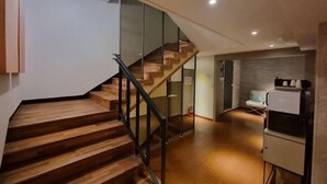 A modern interior with a wooden staircase, glass railings, and a kitchenette area. - Hound Hotel Seomyeon-bumcheon (Busan)