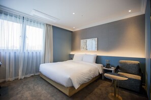 A hotel room with a large bed, a bedside table with a lamp, a chair, and a window with curtains. - Hound Hotel Seomyeon-bumcheon (Busan)