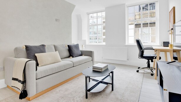 Una sala de estar moderna con sofá, mesa de centro y escritorio con silla.