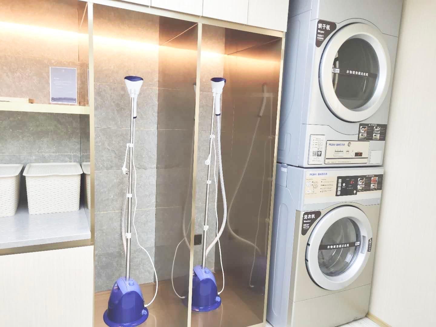 A laundry area with two dryers, a washing machine, and a shelf with baskets.