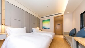 Quarto de hotel com uma cama grande, mesas de cabeceira, uma TV e um quadro na parede.