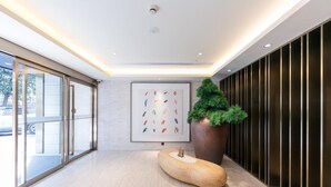 A modern lobby with a large potted plant, a unique wooden sculpture, and a framed artwork on the wall. - Ji Hotel Shanghai Stadium (Shanghai)
