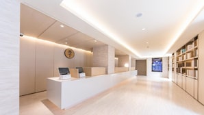 Uma receção moderna com totens digitais, um interior minimalista e vista para a área de receção.