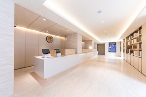 Un comptoir d’accueil moderne doté de bornes numériques, un intérieur minimaliste et une vue sur l’espace d’accueil.