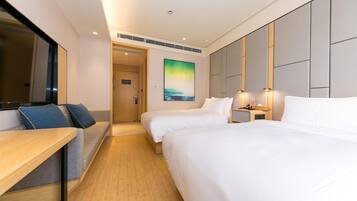 Quarto de hotel com duas camas, uma mesa, um sofá e um quadro na parede.