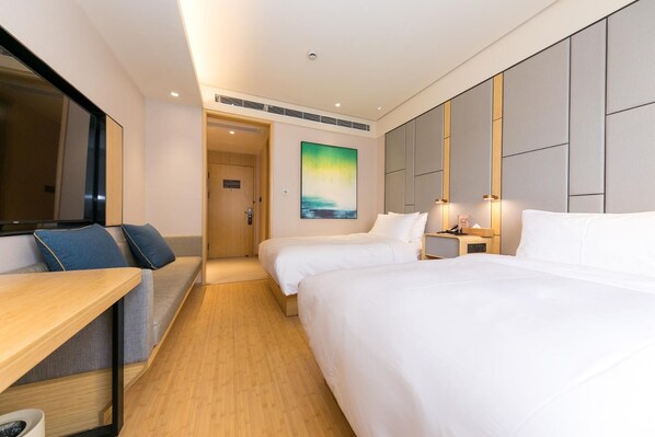 Une chambre d’hôtel avec deux lits, un bureau, un canapé et un tableau au mur.