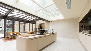A modern kitchen with a large island, built-in appliances, and a glass enclosure. - Ji Hotel Shanghai Stadium (Shanghai)