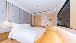 Quarto de hotel moderno com cama grande, guarda-roupa embutido e espelho amplo.