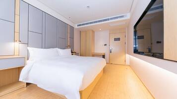 Quarto de hotel moderno com cama grande, guarda-roupa embutido e espelho amplo.