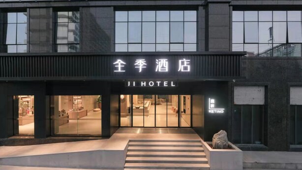 Entrada de hotel com fachada moderna, escadaria visível que leva à entrada e placa com o nome do hotel.