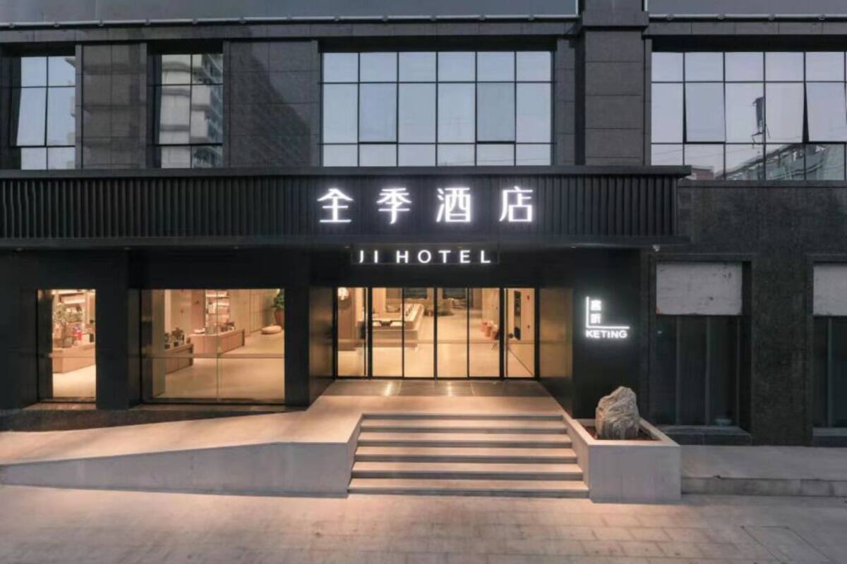 A hotel entrance with a sign reading 'JI HOTEL' and a visible interior through the glass doors.