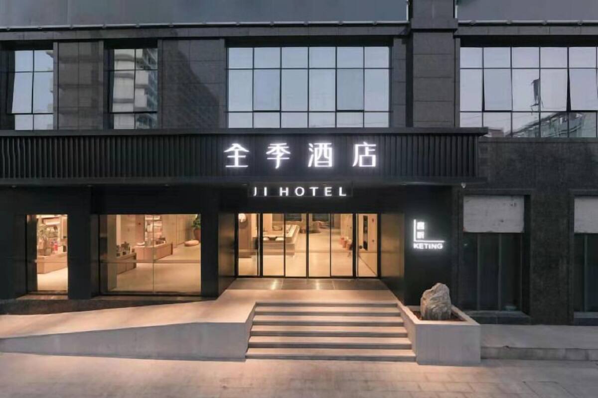 A hotel entrance with a modern facade, large glass doors, and a visible staircase leading to the entrance.