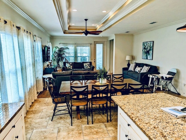 A spacious living area with a dining table, chairs, a sofa, and a kitchen area with granite countertops.