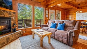 L’intérieur chaleureux d’un chalet avec une cheminée, un canapé doté de coussins bleus et un coin repas.