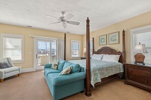 A bedroom with a four-poster bed, a ceiling fan, and a view through the door. - Best of My Love:Oceanfront, heated pool, hot tub, elevator, rec and theater room (Kill Devil Hills)