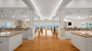 A spacious kitchen with high ceilings, large windows, and a central island. - Take It to the Limit: 16 Bedrooms, oceanfront, pool, elevator, hot tubs, rec room, theater room! (Nags Head)