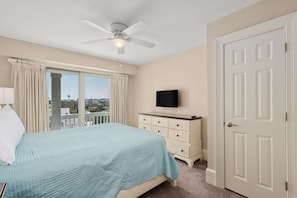Ein Schlafzimmer mit einem Bett, einem Deckenventilator, einem Fernseher, einem Schminktisch und einer Tür.