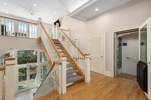 Un interior espacioso con una escalera de madera, un vidrio que da al exterior y vistas del entorno.