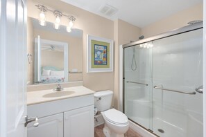 A bathroom with a sink, toilet, mirror, and glass-enclosed shower.