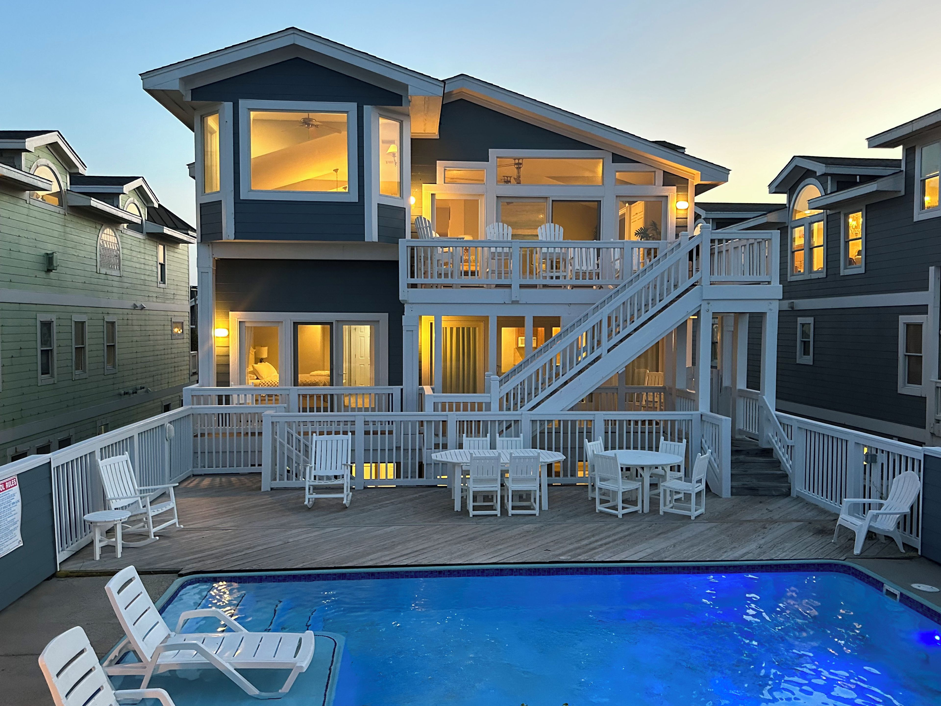 A multi-story house with a pool, outdoor seating, and a staircase.