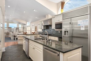 A modern kitchen with stainless steel appliances, a granite countertop, and a view to the outside.