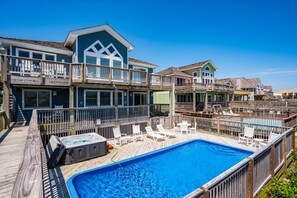 A multi-story house with a swimming pool, wooden deck, and outdoor seating. - Tequila Sunrise-Oceanfront w/views, private pool, hot tub, rec room w/pool table (Nags Head)
