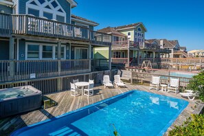 Enjoy a balcony with a view of the water from this two-story residence, featuring a pool and lounge chairs.