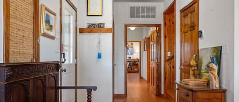 A hallway with wooden floors, a bench, and a wooden cabinet with a painting.