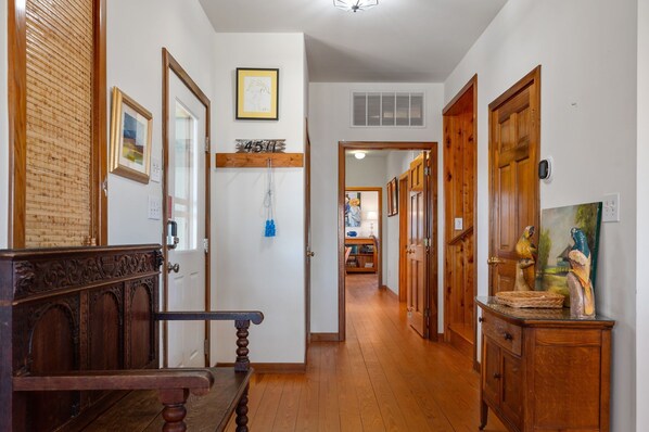 A hallway with wooden floors, a bench, and a wooden cabinet with a painting.
