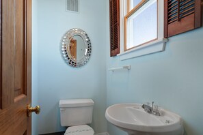 A bathroom with a toilet, sink, and a decorative mirror.