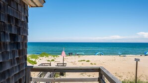 A wooden beach house with a deck overlooking a sandy beach and the ocean. - Gillam Hall: Oceanfront, private walkway, tons of space and beautiful beaches. (Nags Head)