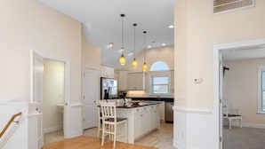 A spacious kitchen with a central island, pendant lighting, and a view of the adjacent dining area.