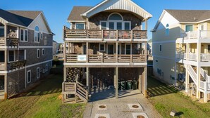 A multi-story residential building with a central balcony, a garage, and a sign indicating it is part of Coastal Carolina. - Phelps Brothers Too:Ocean Views, Private pool, hot tub, elevator & Dog Friendly! (Nags Head)