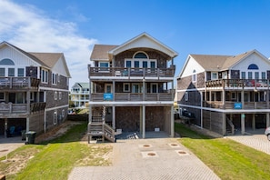 Une propriété située en bord de mer, comprenant plusieurs niveaux, un espace extérieur aménagé et une zone couverte.