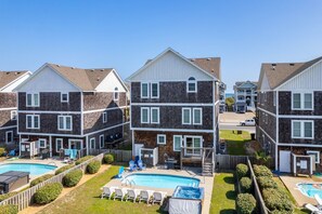 Un ensemble résidentiel comprenant plusieurs bâtiments de deux étages, une piscine commune et des espaces de détente extérieurs.