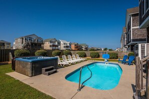 Un complexe résidentiel doté d’une piscine, de chaises longues et d’un jacuzzi.