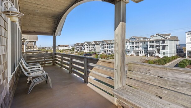 Een houten terras met bankjes, met uitzicht op een rij strandhuizen.