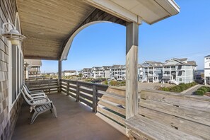 Une terrasse en bois, dotée de bancs, qui offre une vue sur une rangée de maisons de plage.