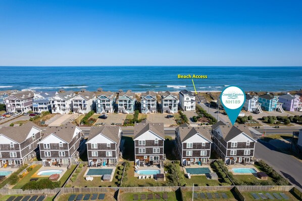 Une zone résidentielle côtière comprenant des maisons, un accès à la plage et un panneau indiquant le site historique Coastal Carolina NH189.