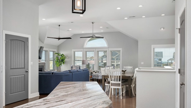 A spacious kitchen with a marble countertop, a dining area with white chairs, and a blue sofa. - Phelps: Semi-oceanfront w/private pool, hot tub, rec and media room & elevator! (Nags Head)